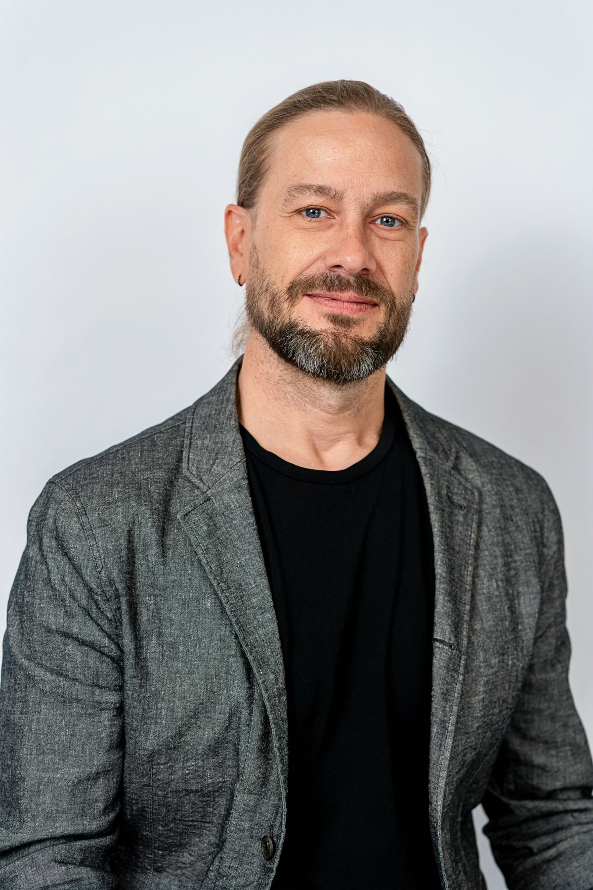 Studio headshot of a man in a charcoal jacket against a pale background
