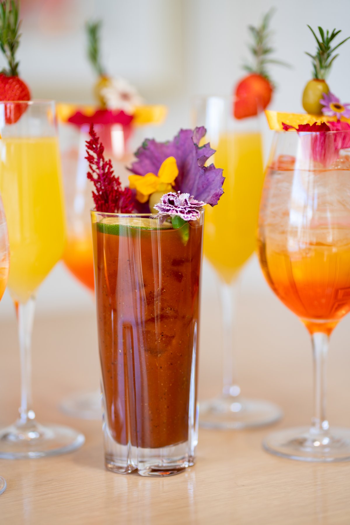 Garnished cocktails arranged around a tall Bloody Mary