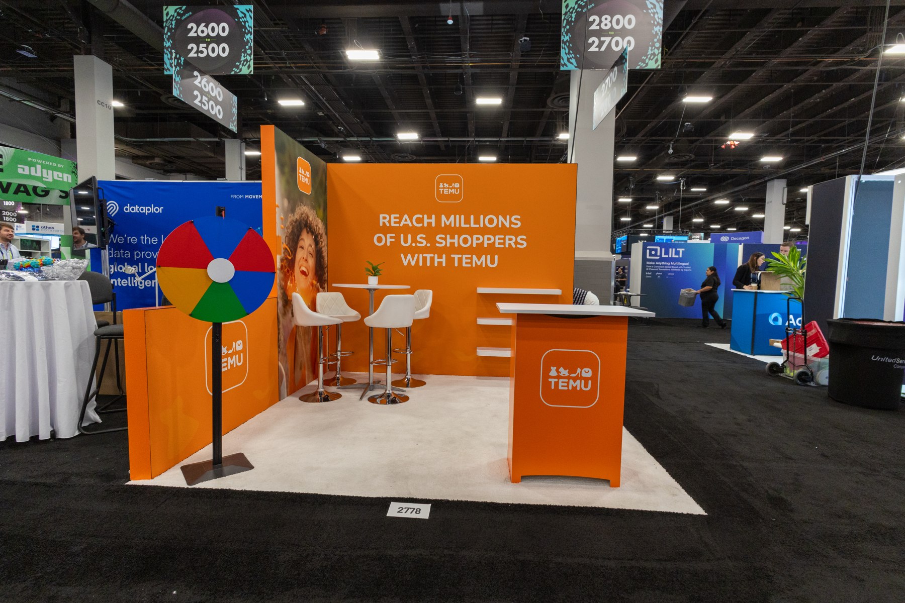 Orange exhibition booth with white seating and branded counter