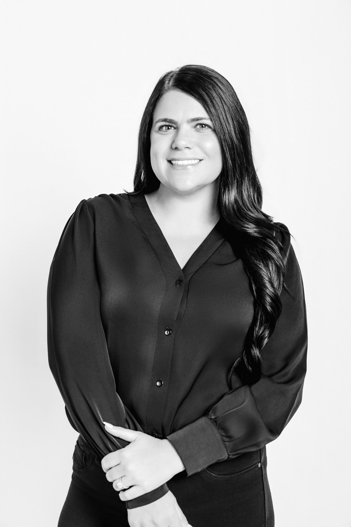 Black-and-white portrait of a smiling team member in a black blouse against a light backdrop