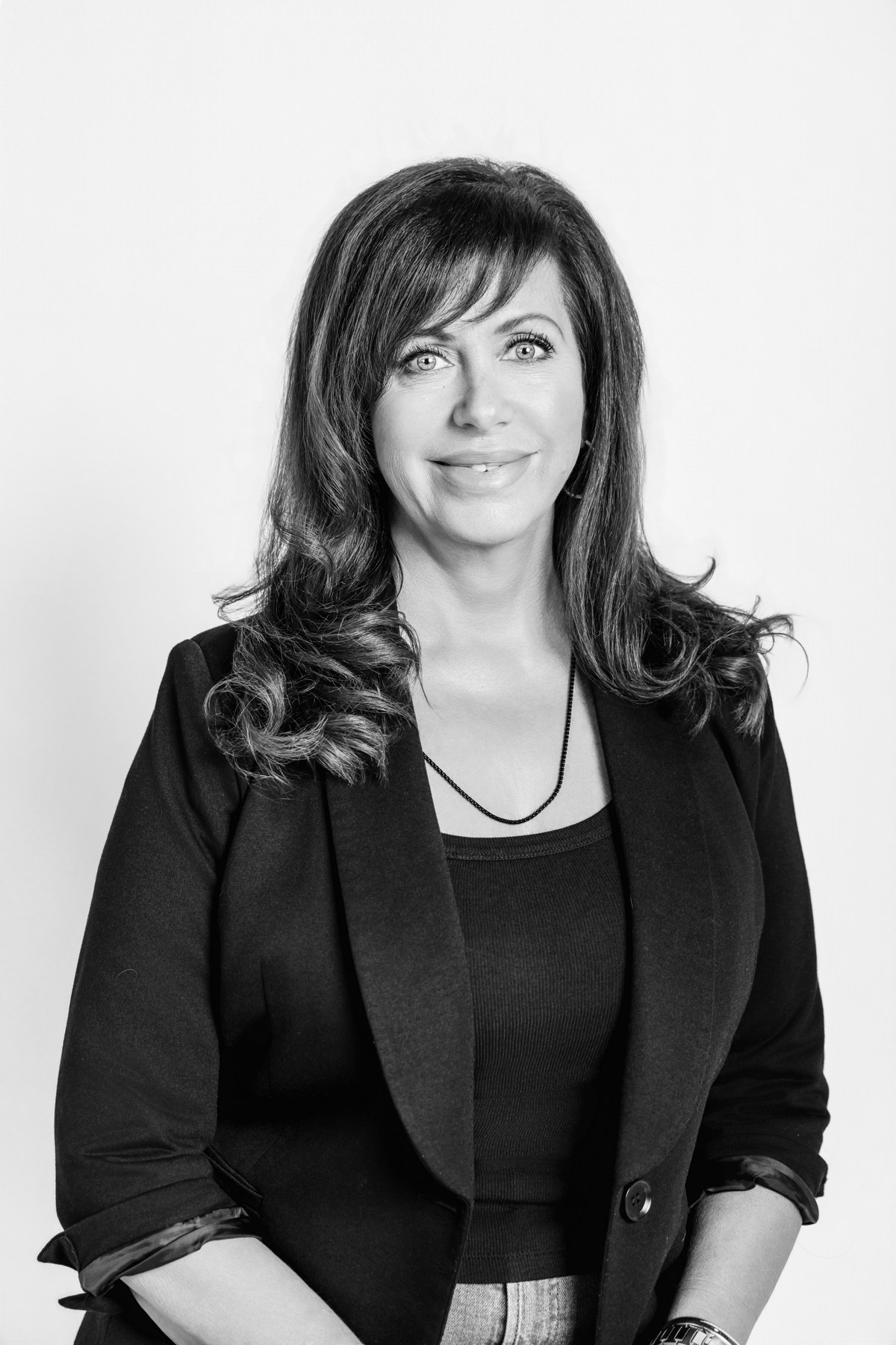 Black-and-white team portrait of a woman in a black blazer with a light background