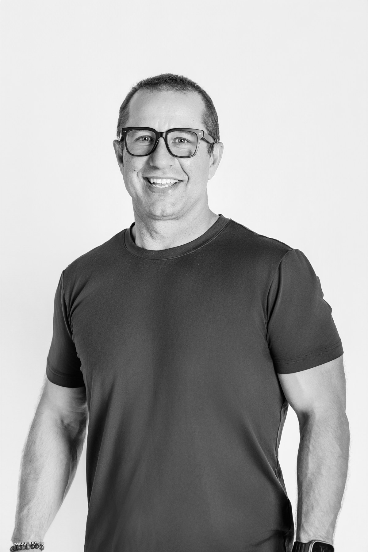 Black-and-white portrait of a smiling team member wearing glasses against a light backdrop