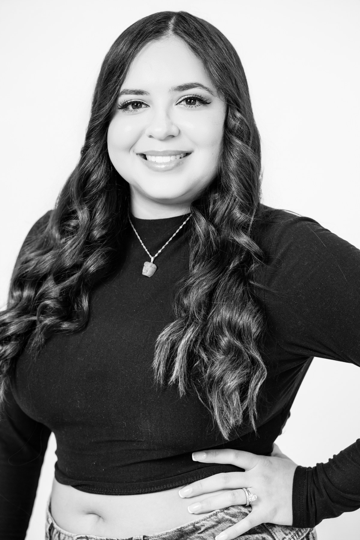 Black-and-white team portrait: smiling team member with long wavy hair in a black top