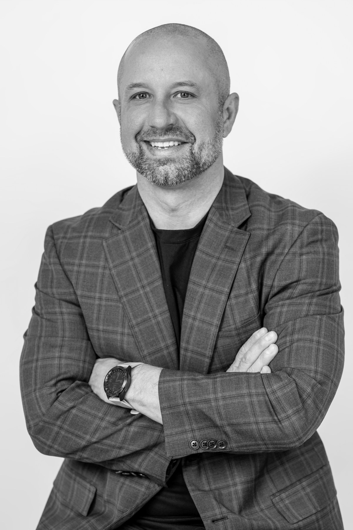Black-and-white team portrait: smiling team member in a checked blazer