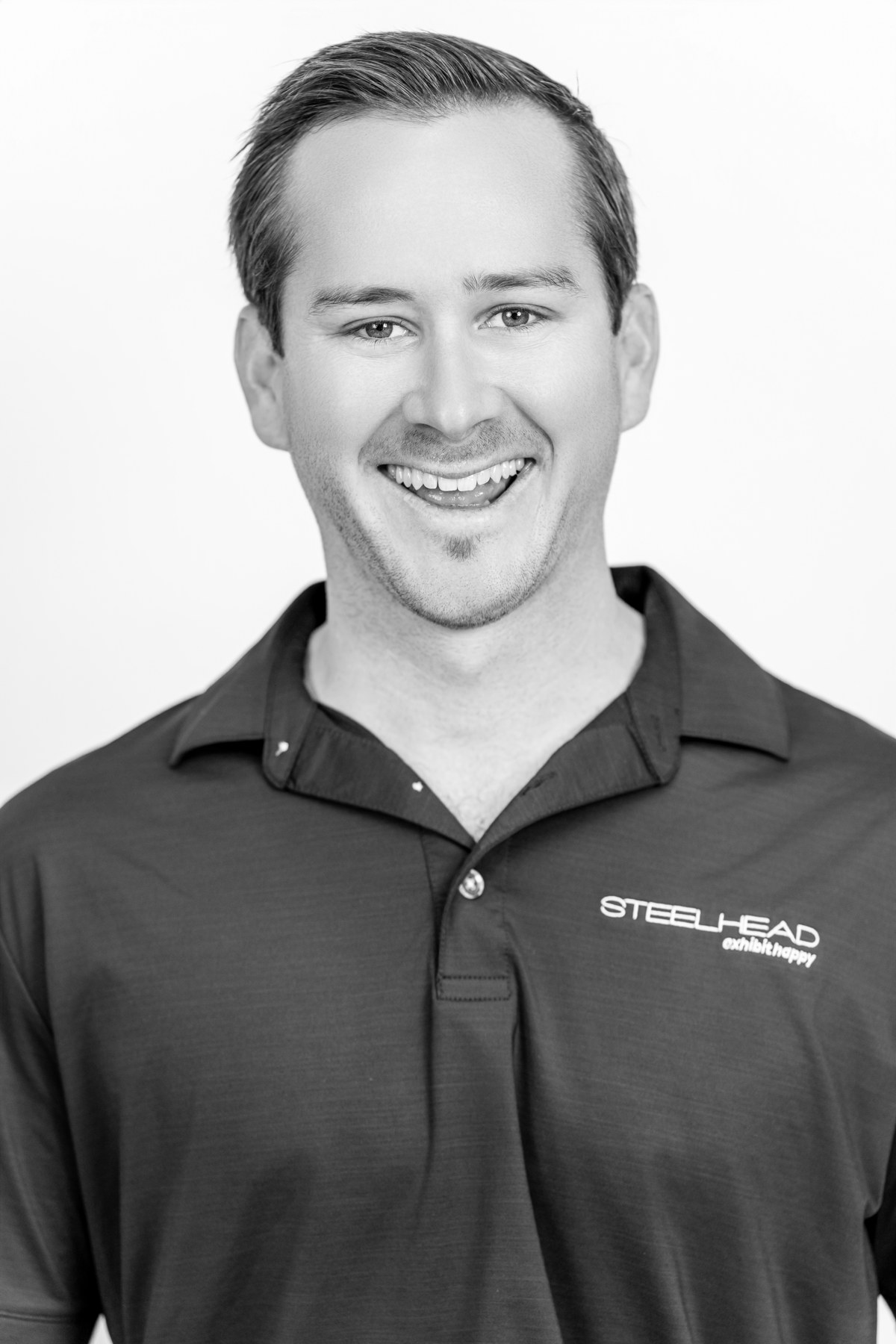 Black-and-white team portrait: smiling team member in a dark polo