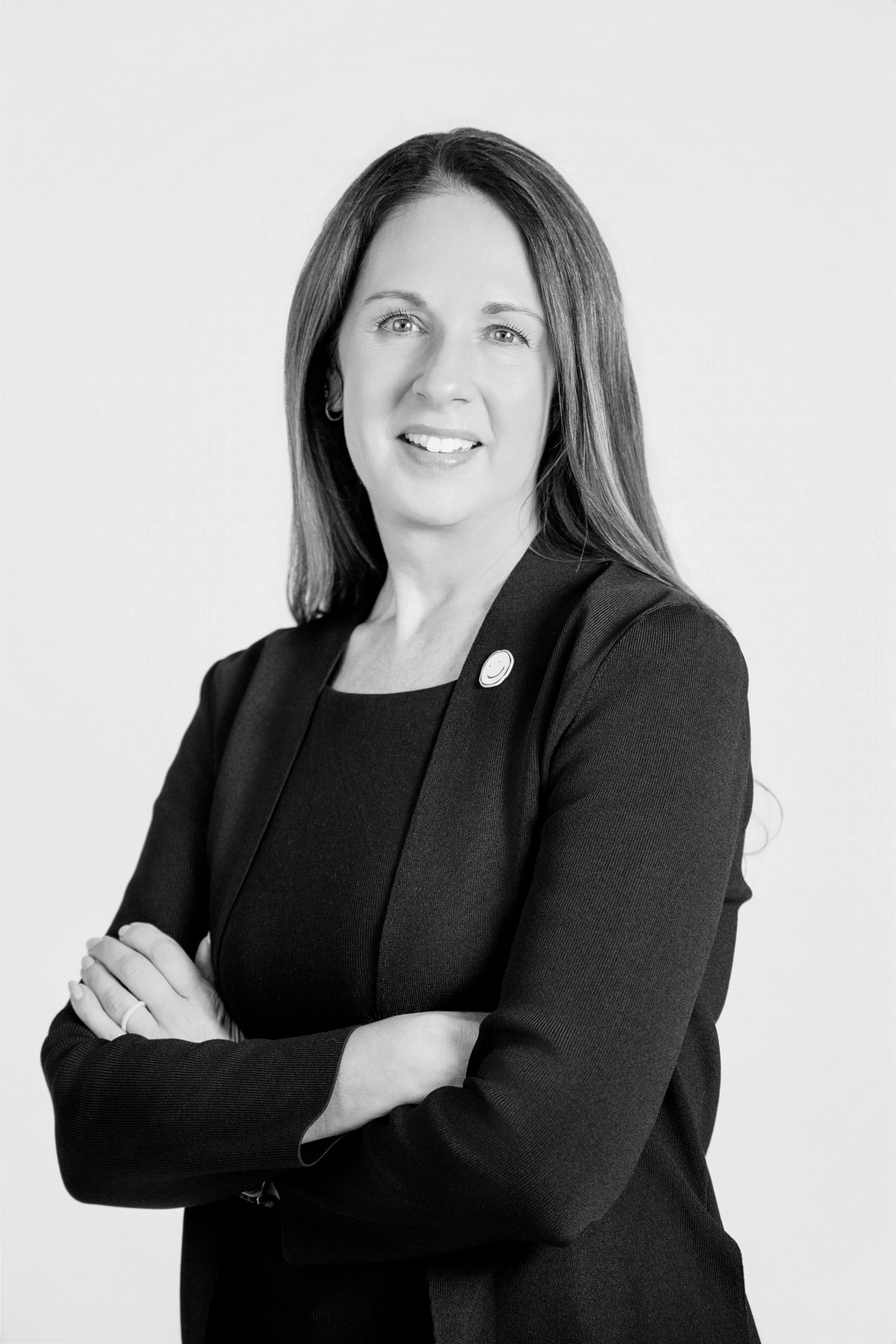 Black-and-white team portrait: team member in a black blazer with folded arms