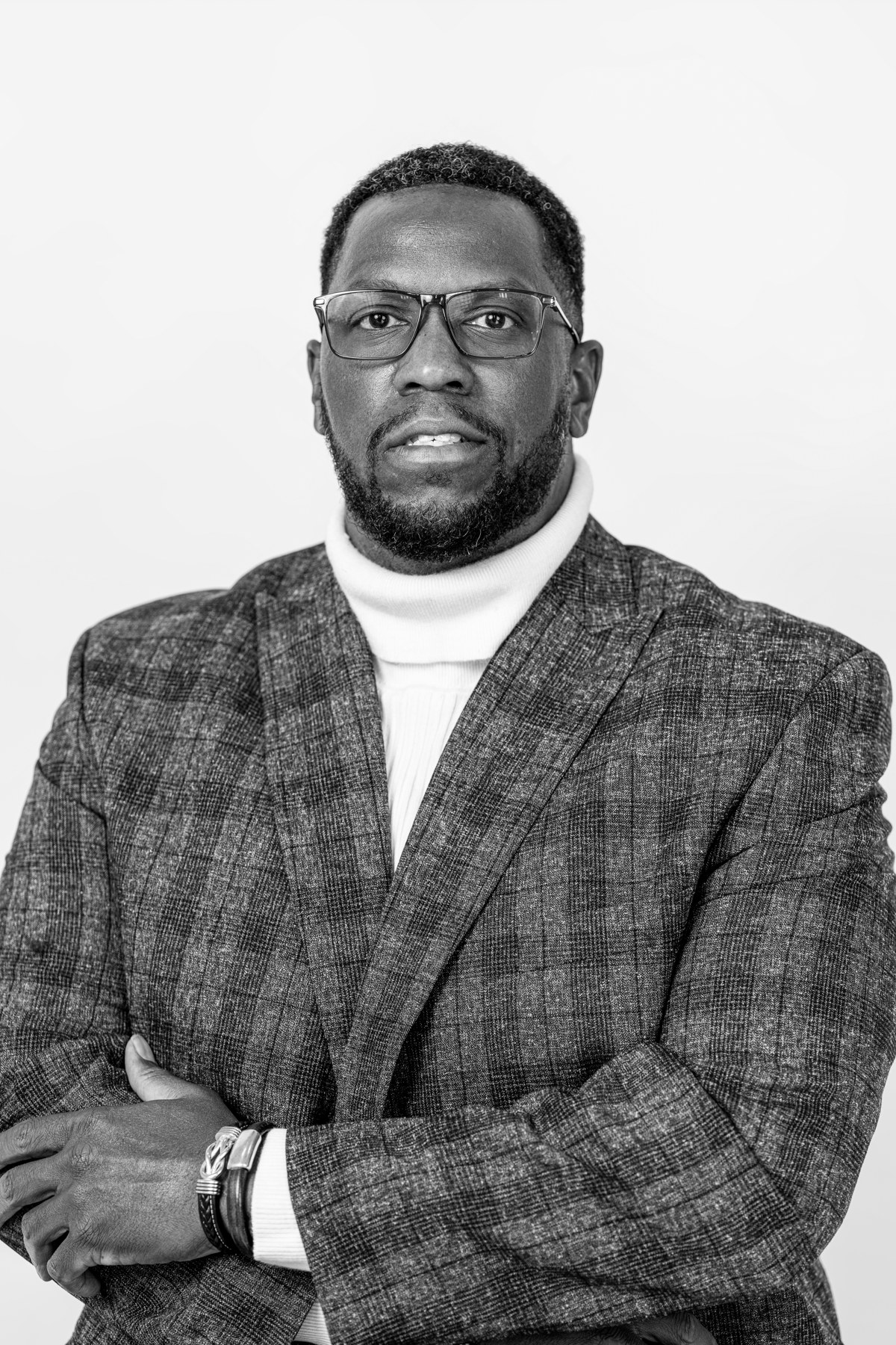 Black-and-white team portrait: team member wearing glasses and a checked blazer
