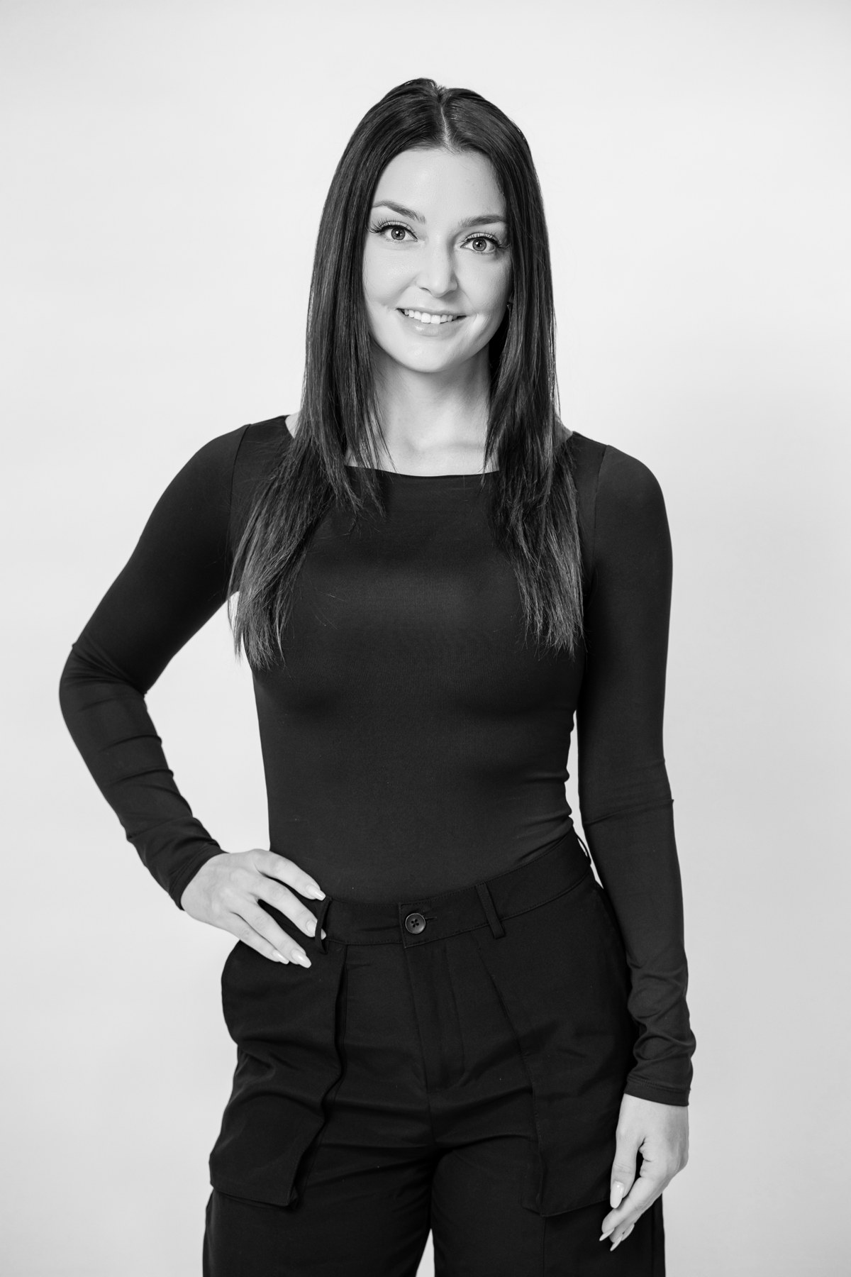 Black-and-white team portrait: team member in a black top with hands on hips