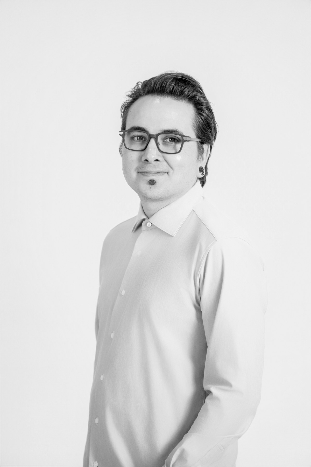 Black-and-white team portrait: team member in glasses and a light button-down shirt