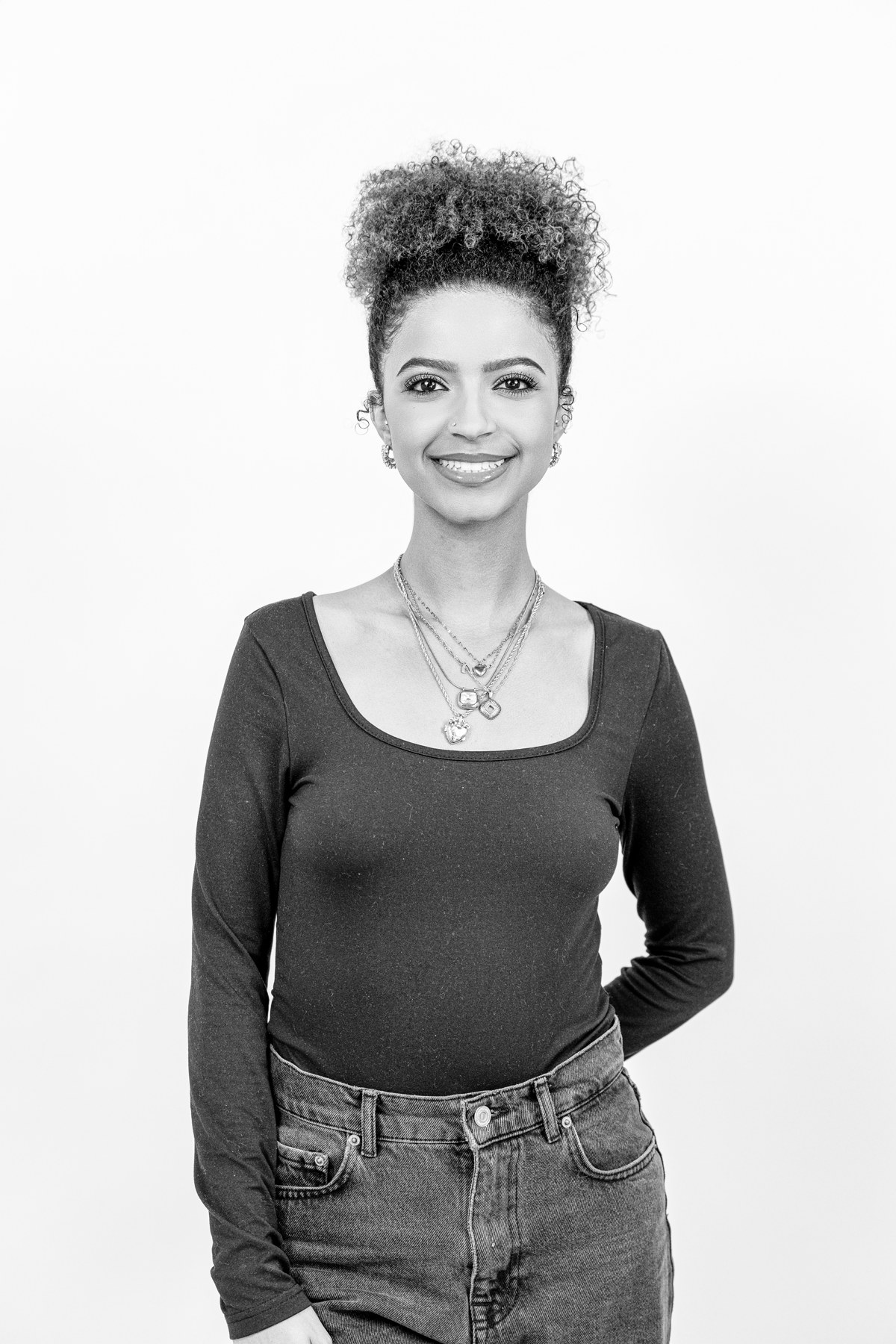 Black-and-white team portrait: smiling team member with an updo in a dark top