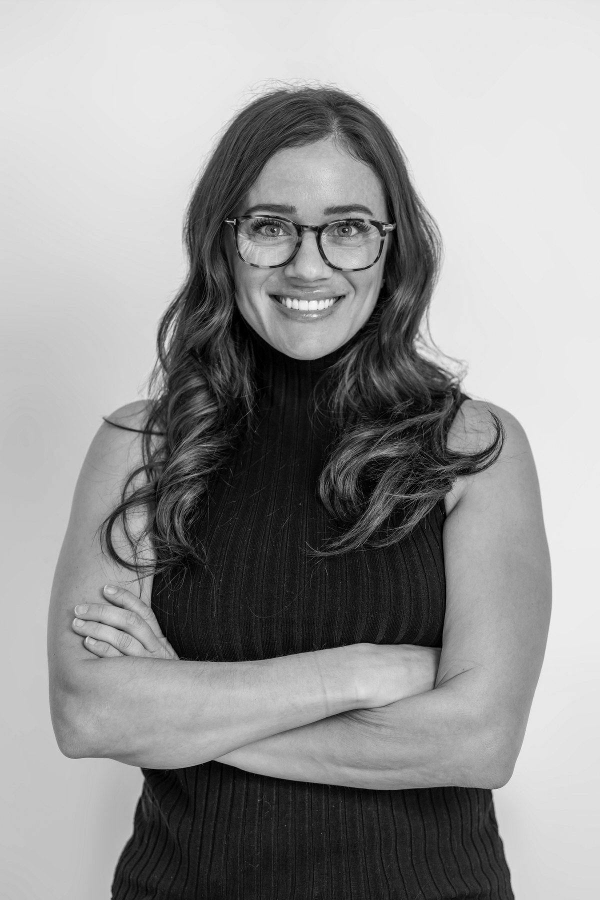 Black-and-white team portrait: smiling team member in glasses and a dark sleeveless top