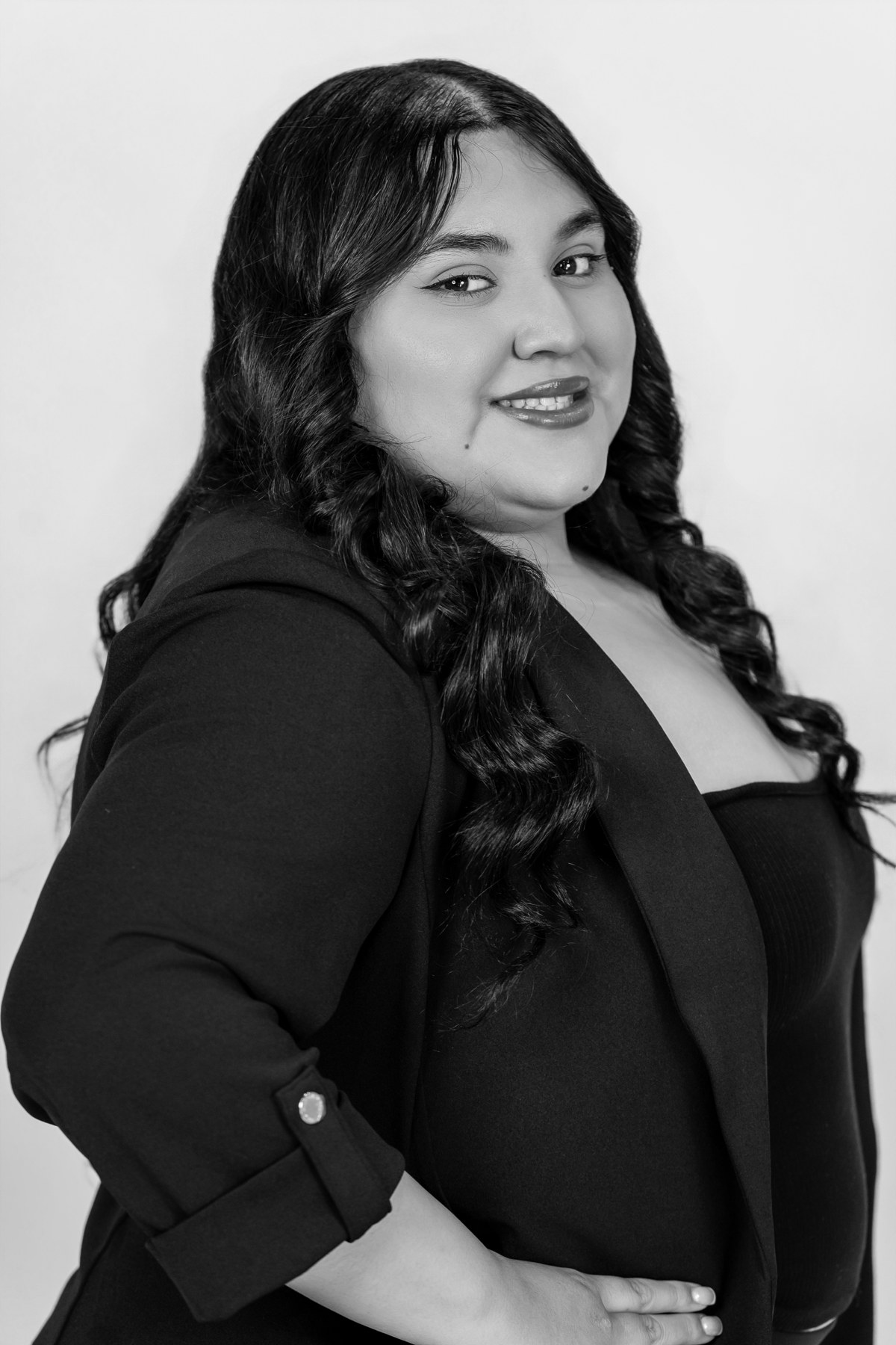 Black-and-white team portrait: smiling team member in a tailored dark blazer
